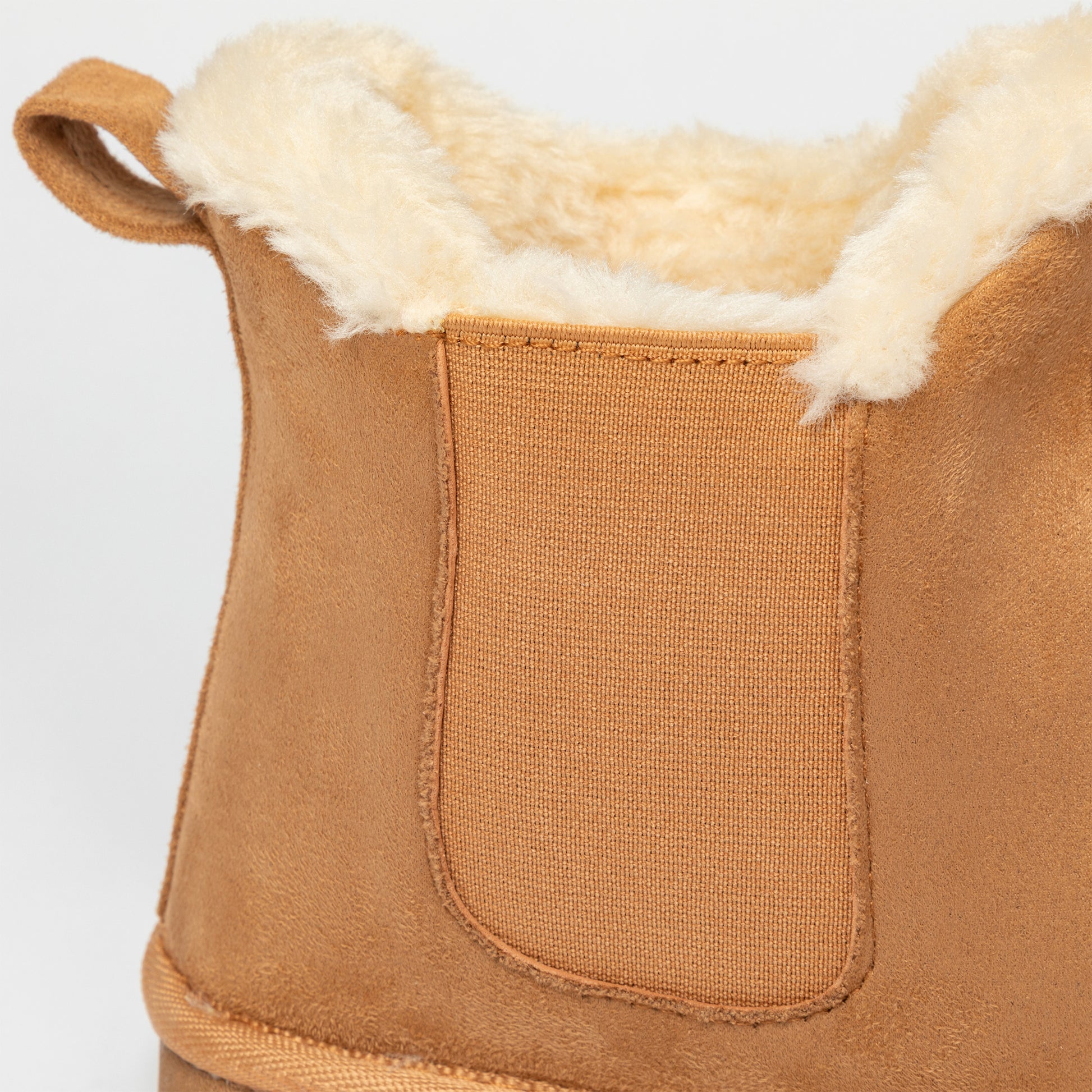 Close-up of a brown suede boot with white fur lining on a light gray background