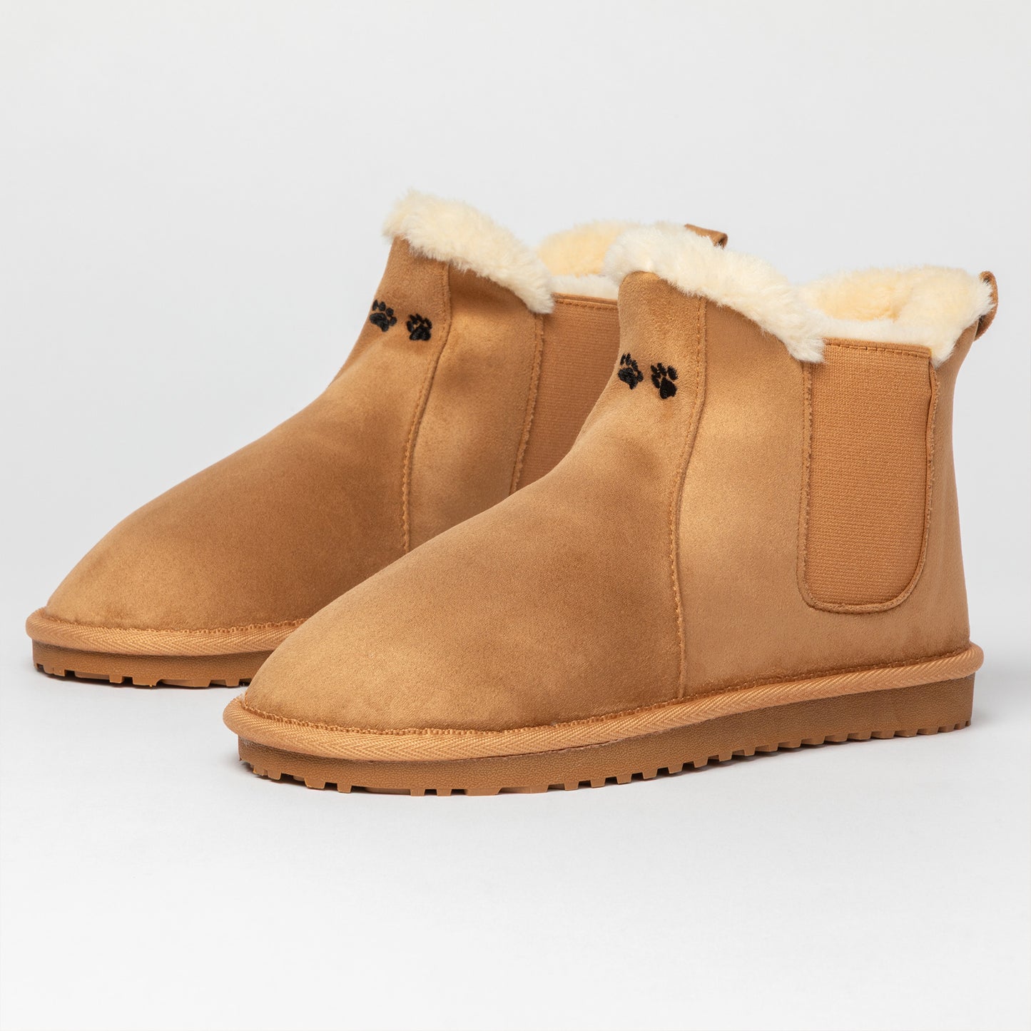 Pair of tan suede boots with fur lining on a light gray background