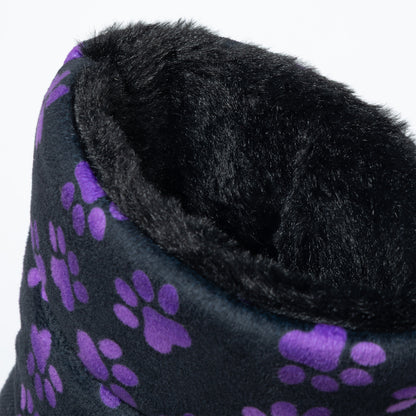 Close-up of a soft black plush slipper boot, featuring a purple paw print pattern on the exterior and a thick black faux fur lining.