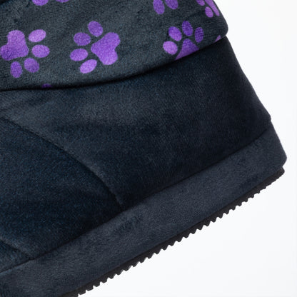 Close-up of a black slipper bootie showing the side profile, textured fabric upper, and a pattern of purple paw prints on the top edge against a white background.