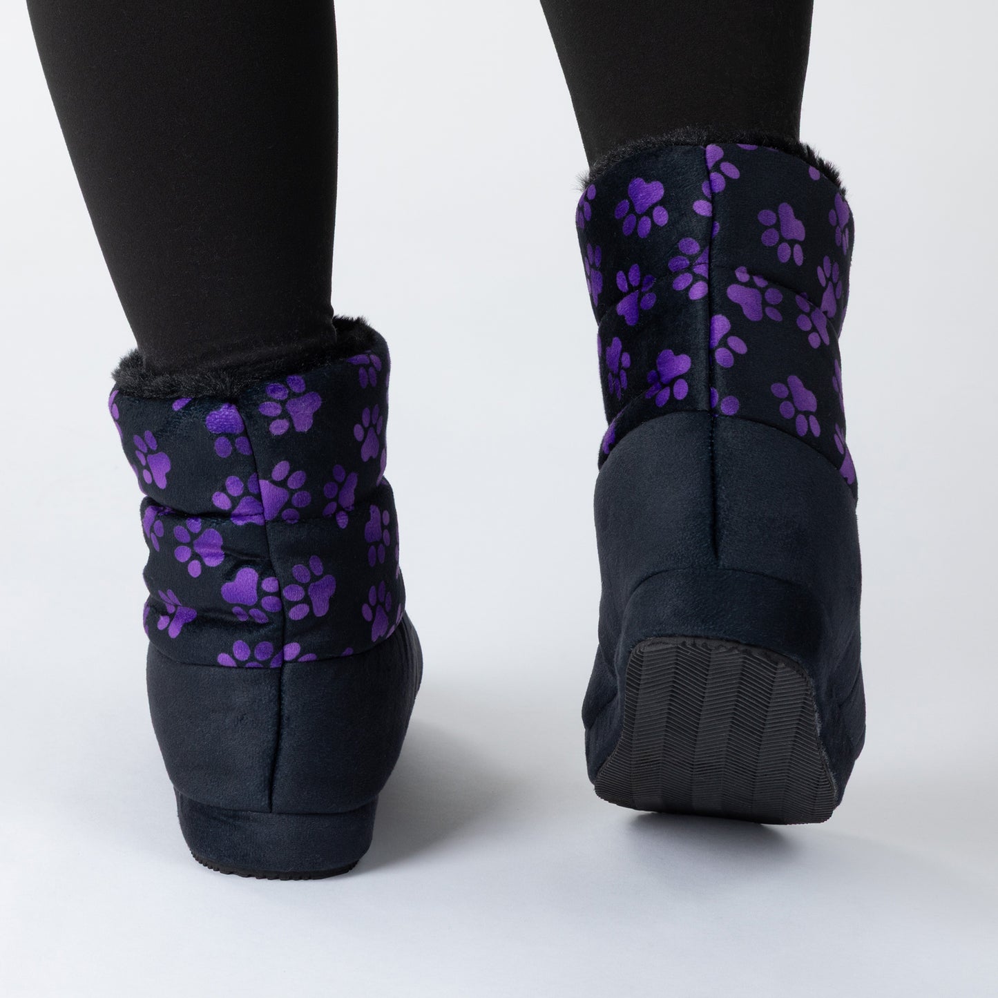 Black ankle boot slippers with purple paw print patterns on the cuffs, shown from the back on a light gray studio background.