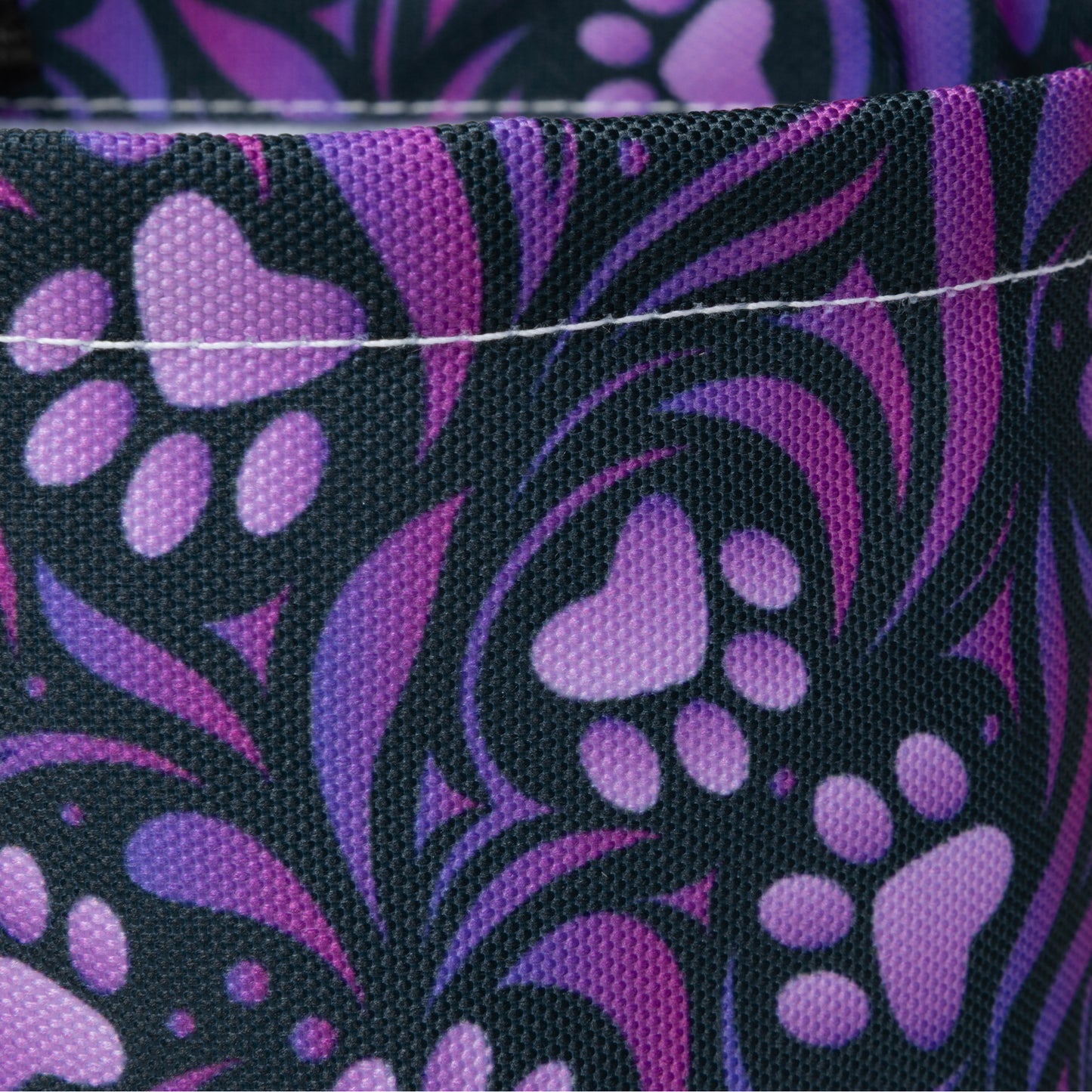 Close-up of fabric with purple paw print pattern on black background