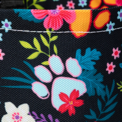 Close-up of a fabric with colorful floral and paw print designs on a black background.
