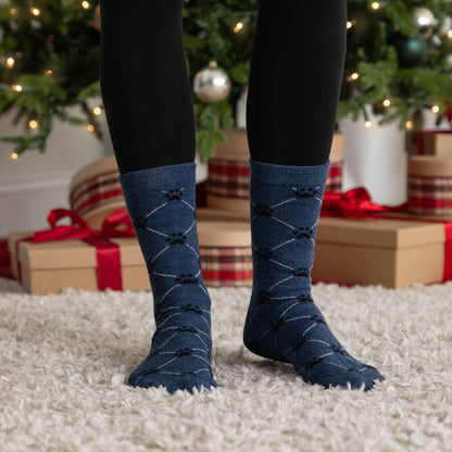 Person wearing blue argyle socks with a Christmas tree and presents in the background