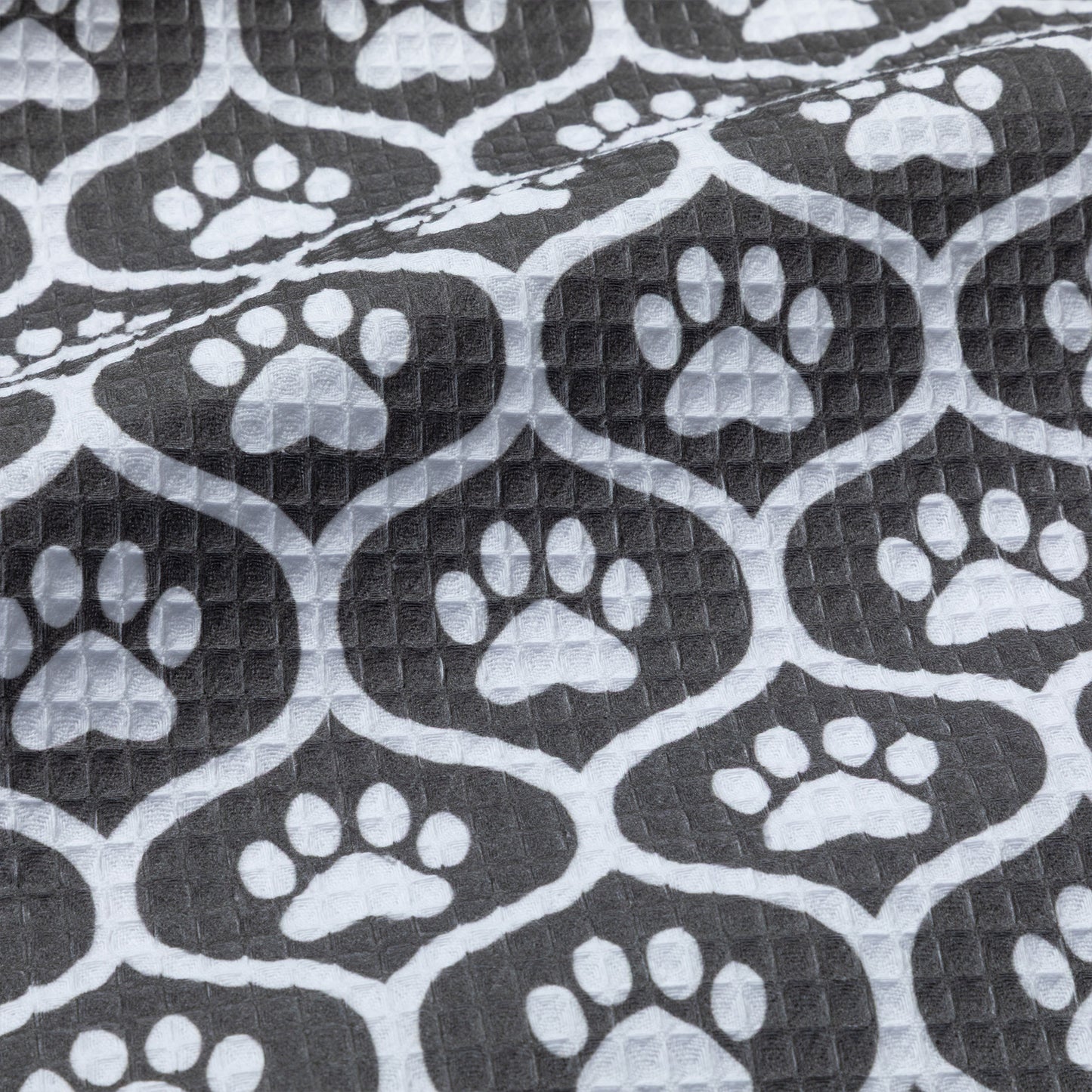 Patterned kitchen towel with white paw prints on a black background