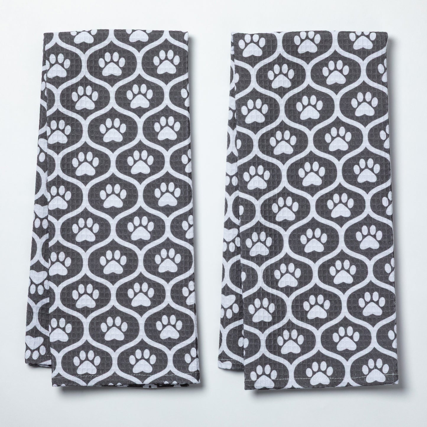 Two folded towels with a pattern of white paw prints on a gray background
