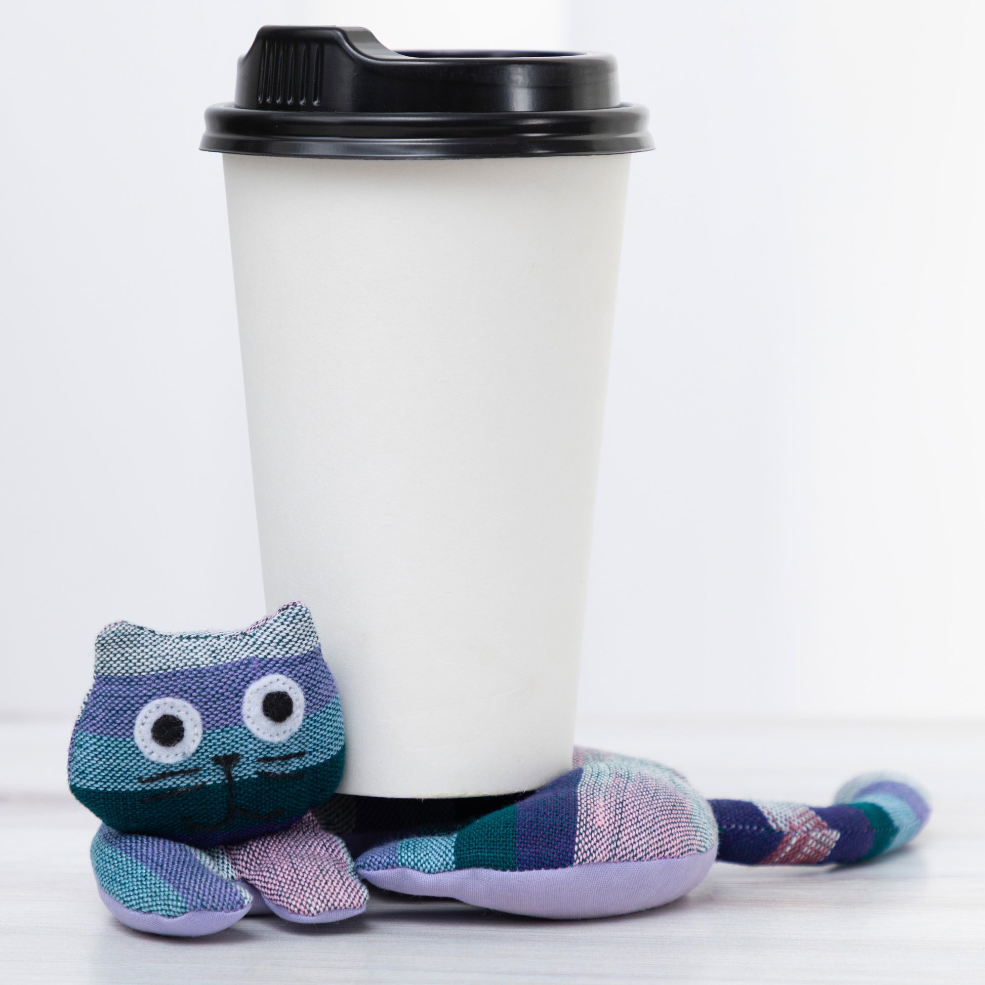 Plush cat shaped coaster with a coffee cup on a white background