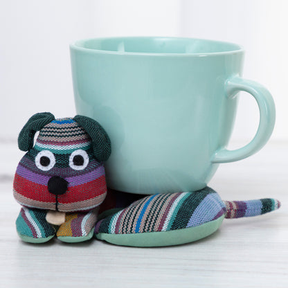 Colorful striped dog-shaped tea cozy next to a light blue mug on a white background
