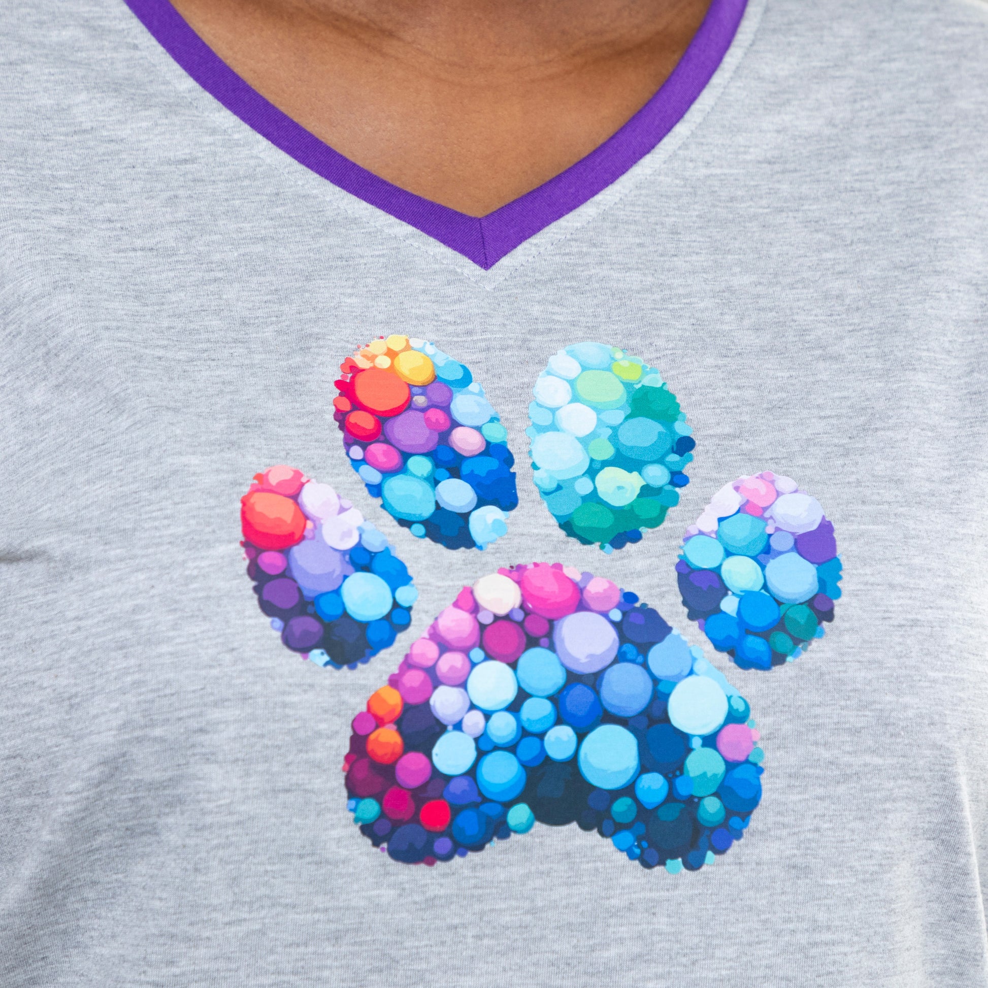 Close up of a gray v-neck shirt with a colorful paw print bubble design on the chest.