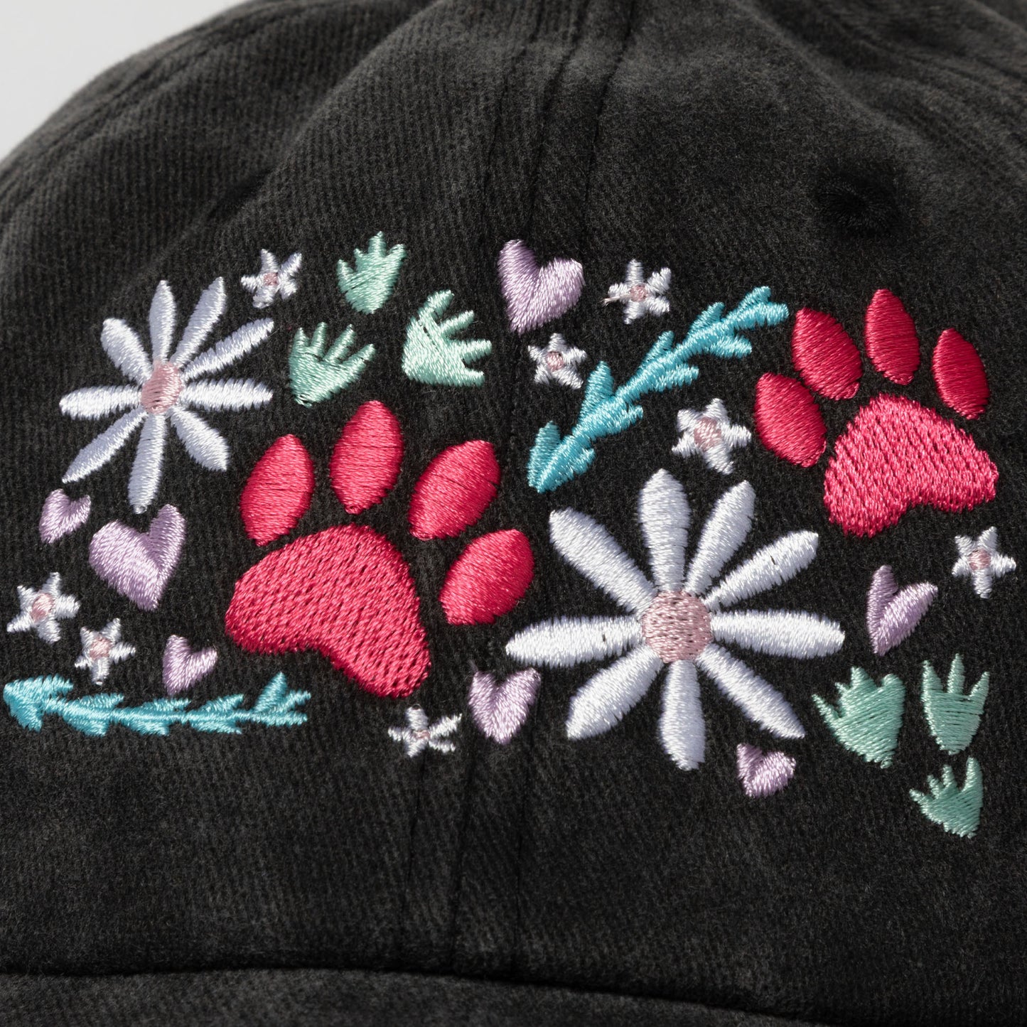 Black cap with pink paw prints, flowers, and leaves on a white background.