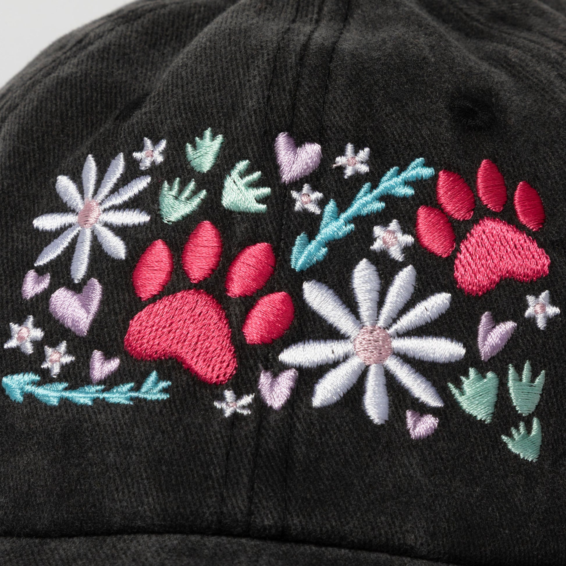 Black cap with pink paw prints, flowers, and leaves on a white background.