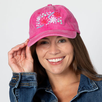 Woman wearing a pink cap with paw print and floral embroidery on a white background