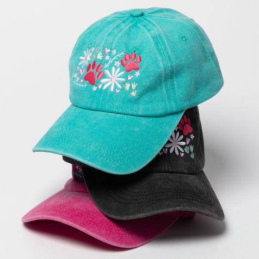 Three cotton baseball caps in turquoise, charcoal gray and fuchsia. Embroidered paws and flowers on the front of each hat.