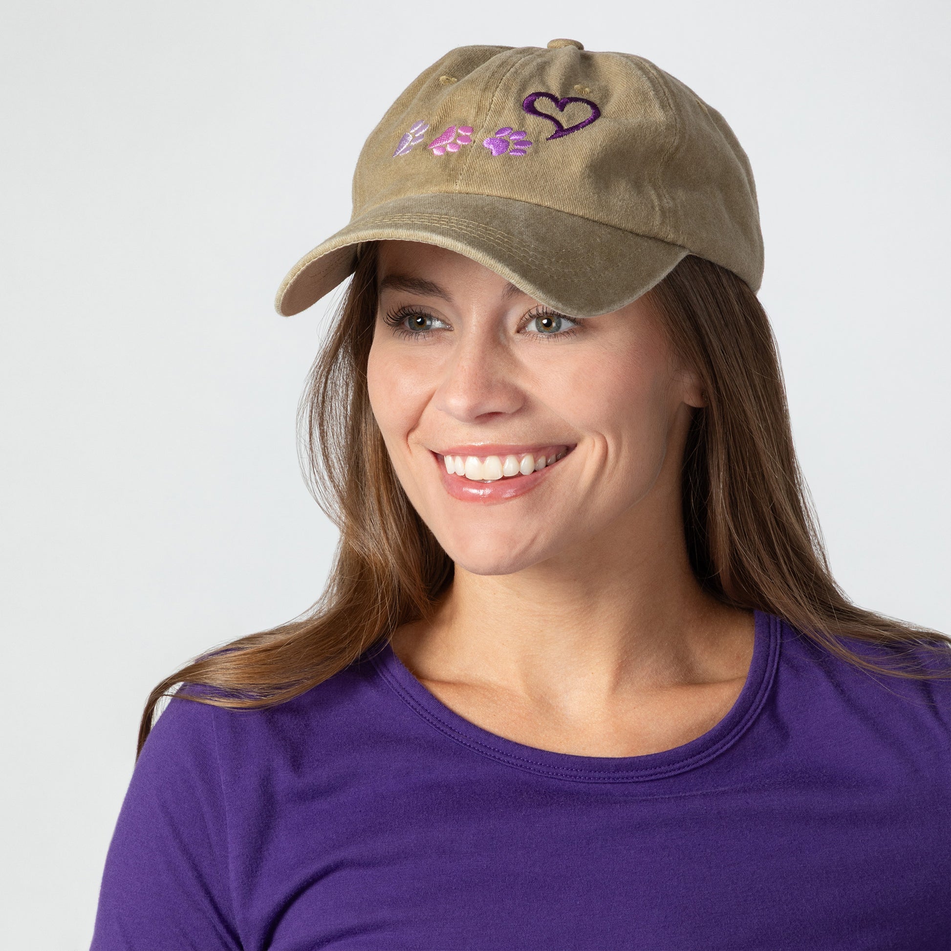 Woman wearing a tan cap with paws and a heart design on a white background