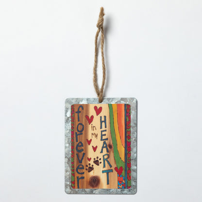 Decorative hanging ornament with "Forever in My Heart" text, hearts and paw prints on a wood background with a heart border on both sides with a rainbow design against a white background