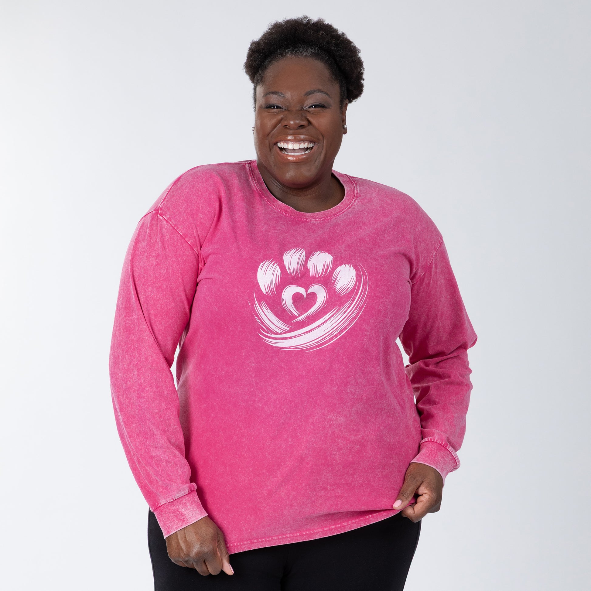 Woman wearing a pink long-sleeve shirt with a heart and paw print design on a white background