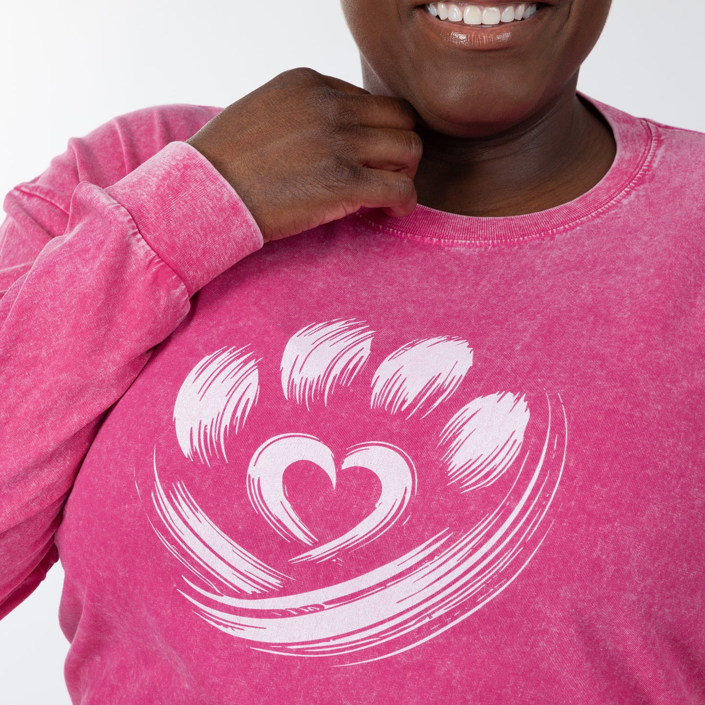 Person wearing a pink long sleeve tee with a white heart design on a plain background