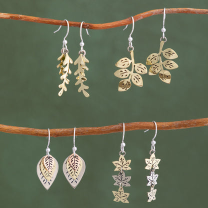 Pairs of leaf-shaped earrings on a branch against a green background
