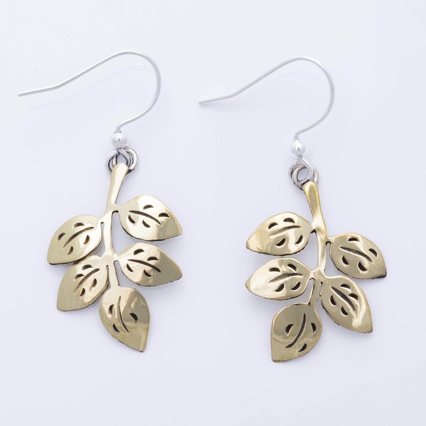Brass leaf-shaped earrings on a white background
