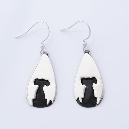 Teardrop-shaped earrings with black and white designs on a light gray background