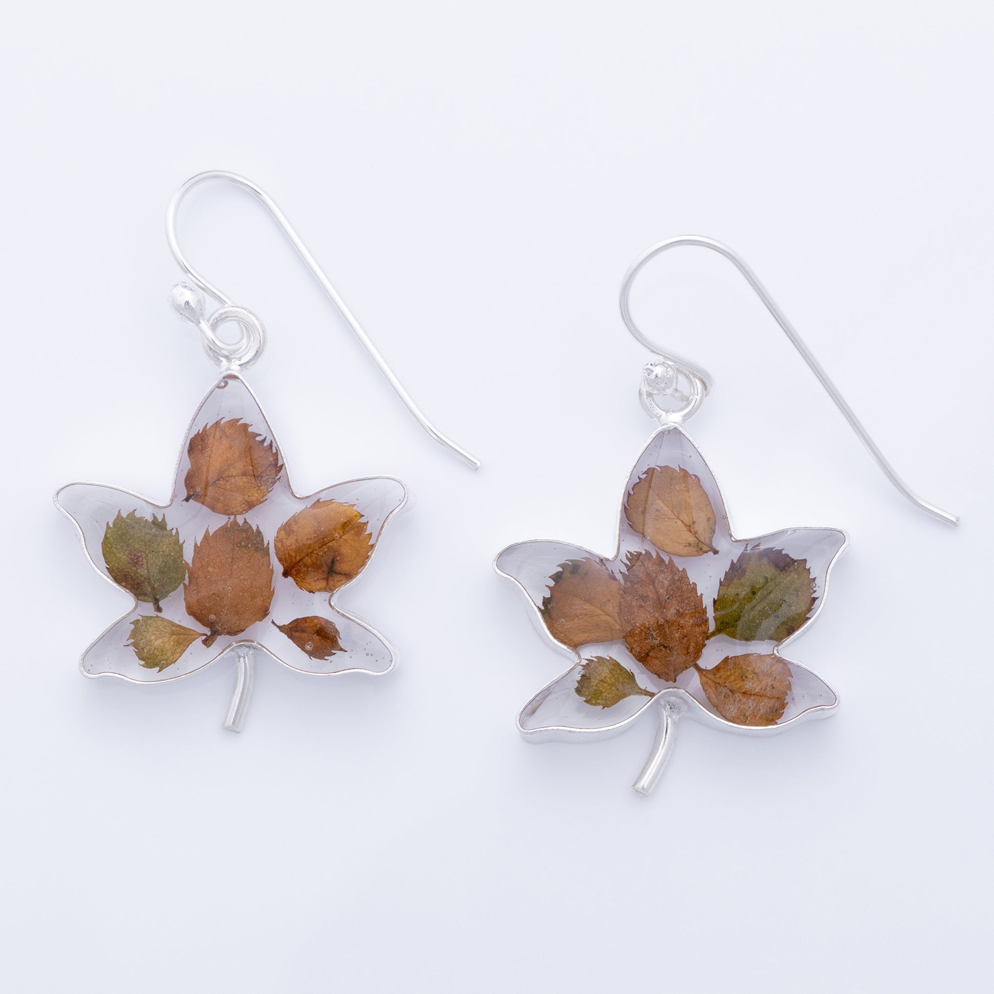 Leaf-shaped earrings with dried leaves on a white background