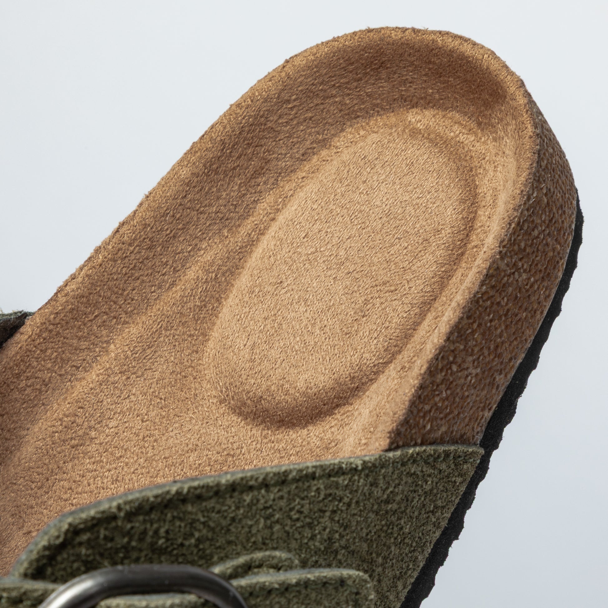 Close-up of a green clog's insole, featuring a textured, cushioned surface.