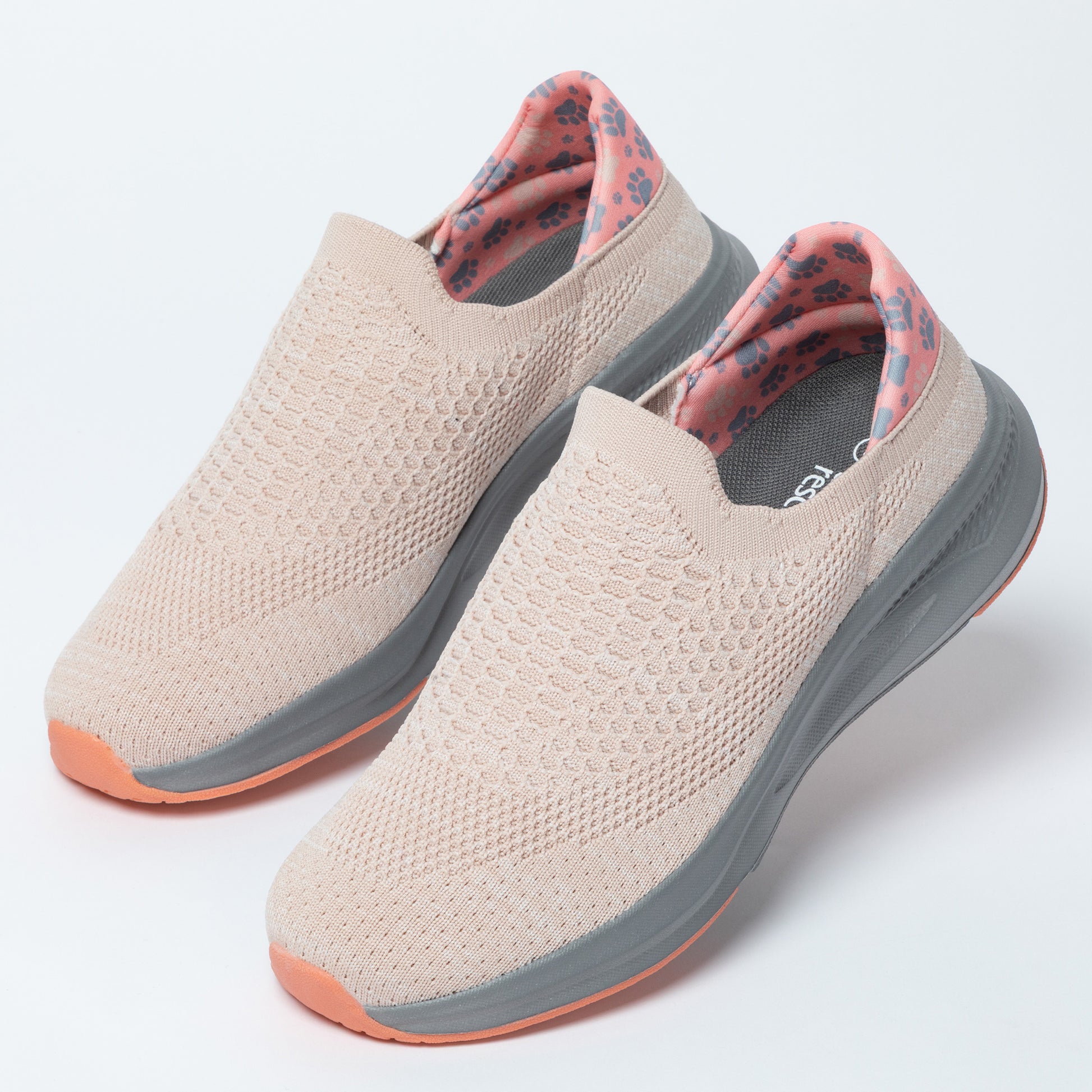 Pair of light pink slip-on shoes with gray soles on a white background