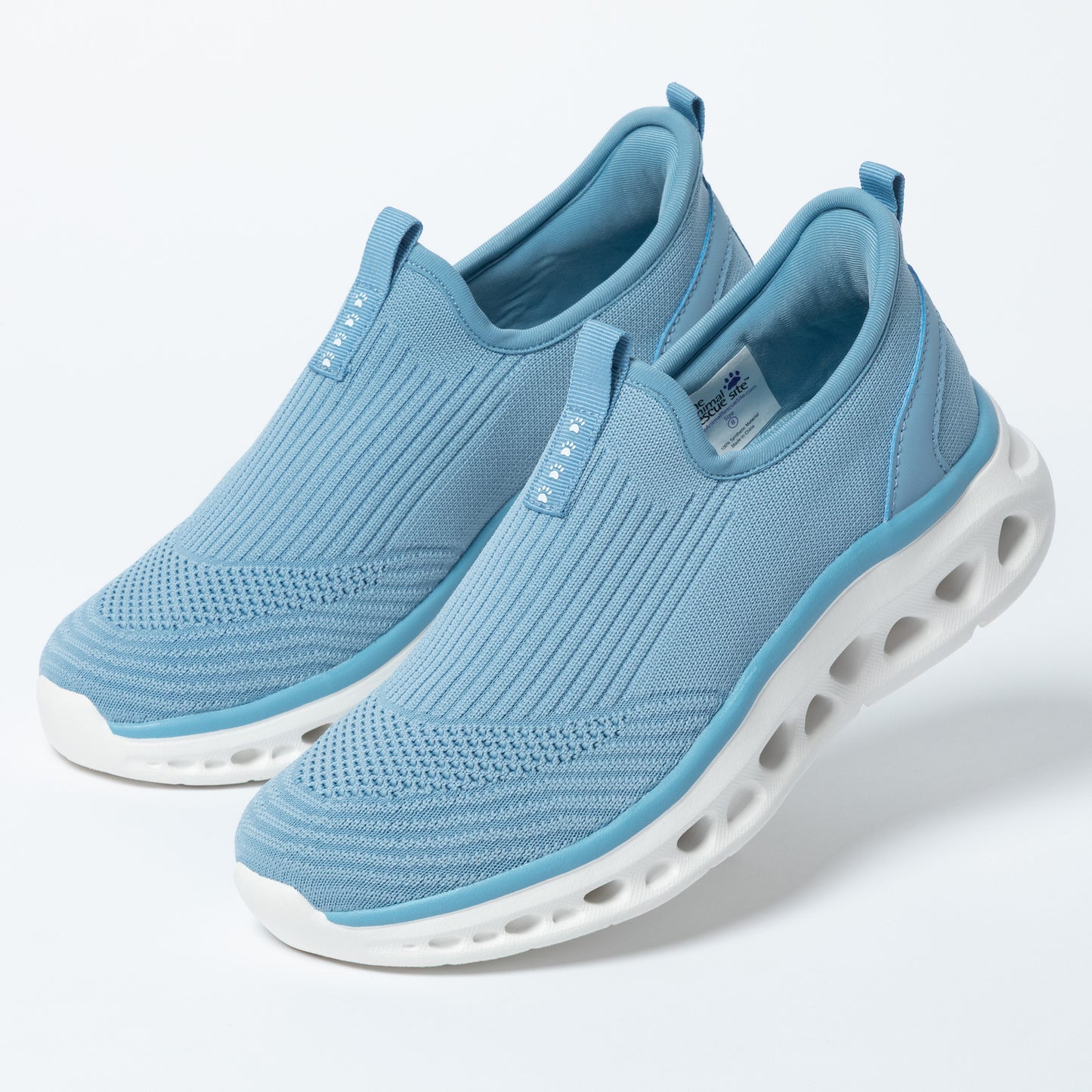 Pair of light blue slip-on shoes with white soles on a light gray background