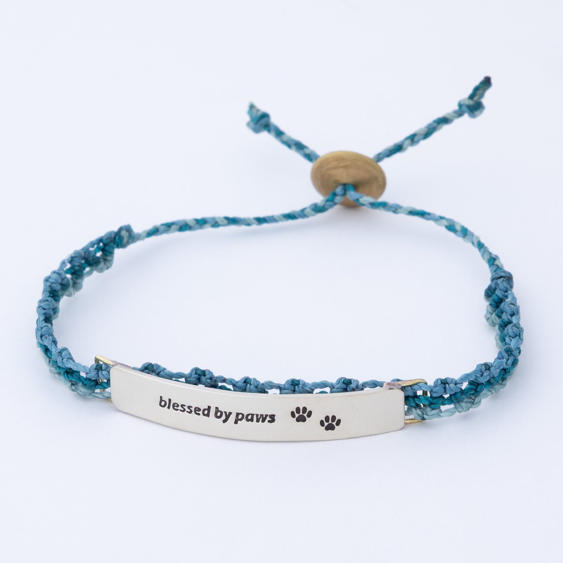 Blue braided bracelet with 'blessed by paws' tag on a white background