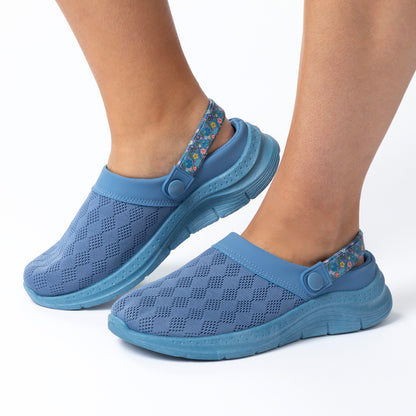 Blue clogs worn on feet with a white background