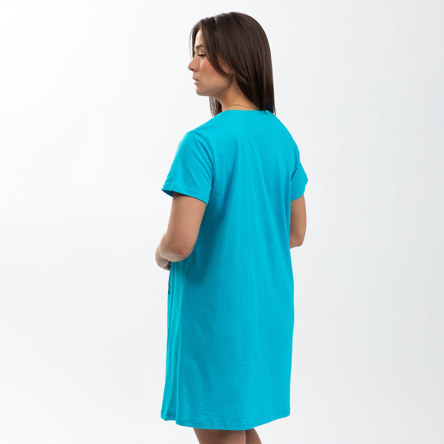 A woman in a bright turquoise nightgown stands facing away, showcasing a relaxed fit.