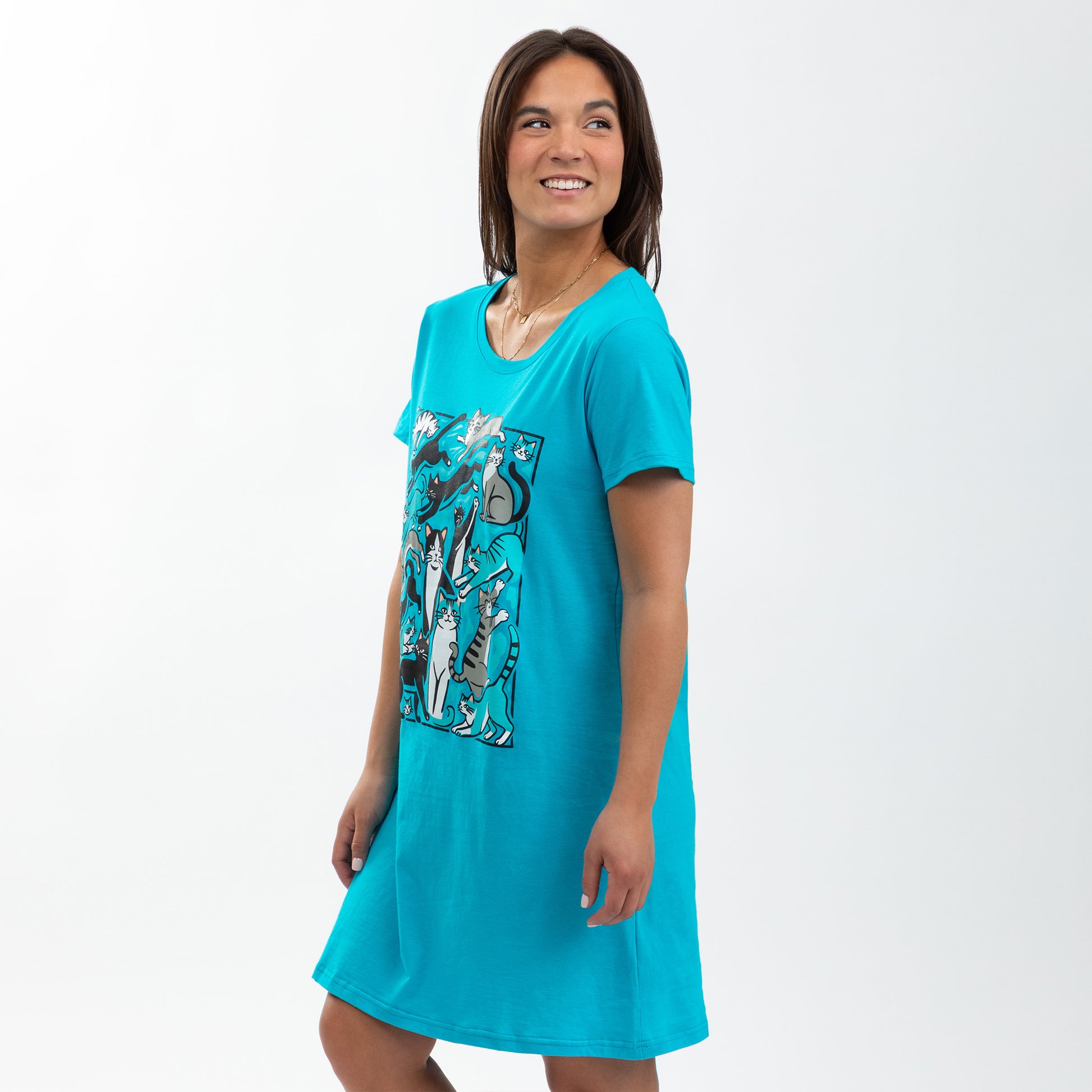 Woman in a blue nightgown featuring playful cat designs, smiling against a light background.