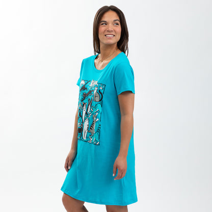 Woman in a blue nightgown featuring playful cat designs, smiling against a light background.