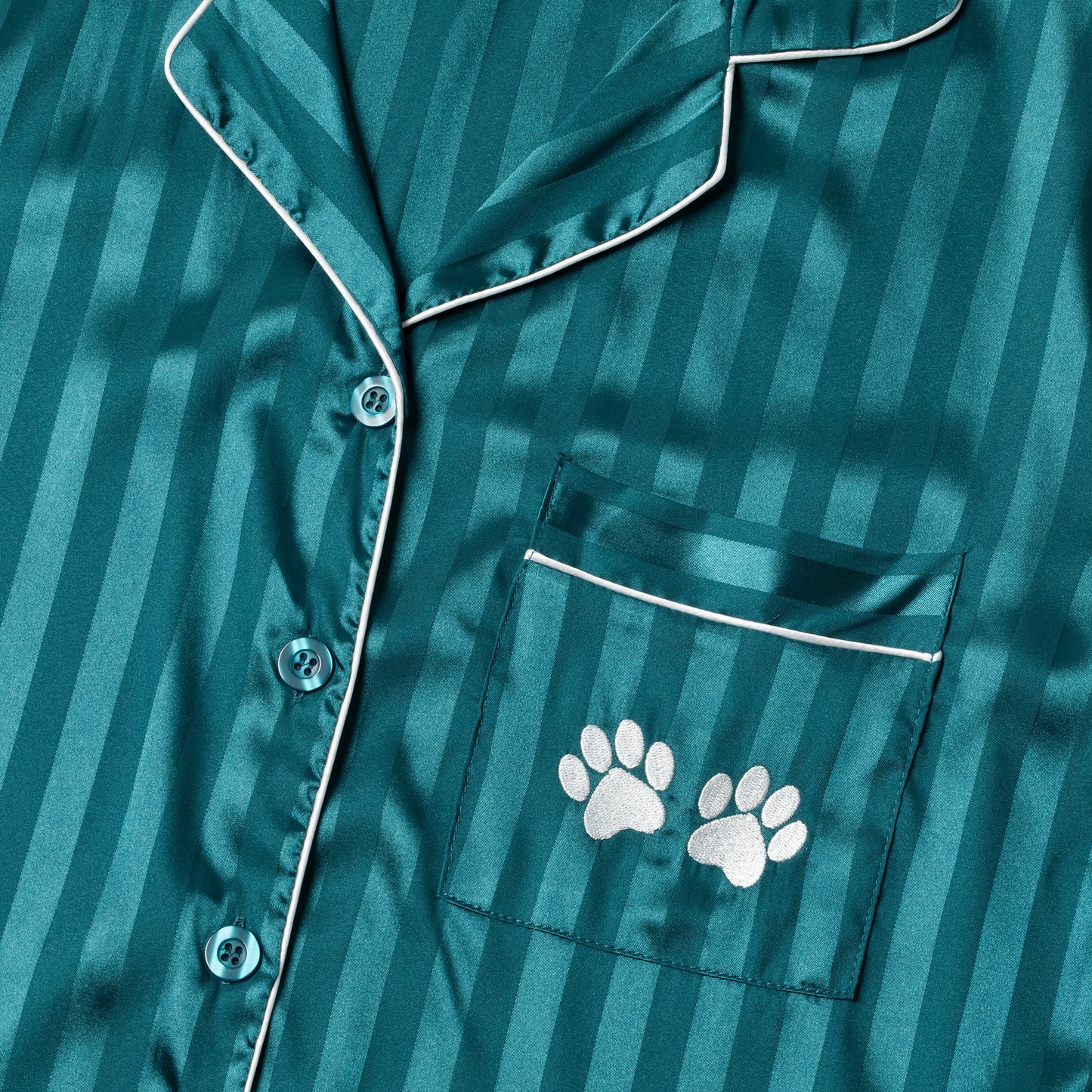 Teal satin pajama top with white paw prints on a striped background