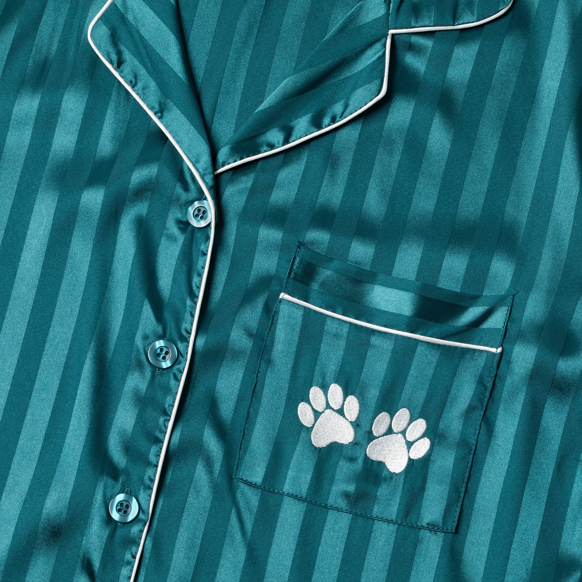 Teal satin pajama top with white paw prints on a striped background