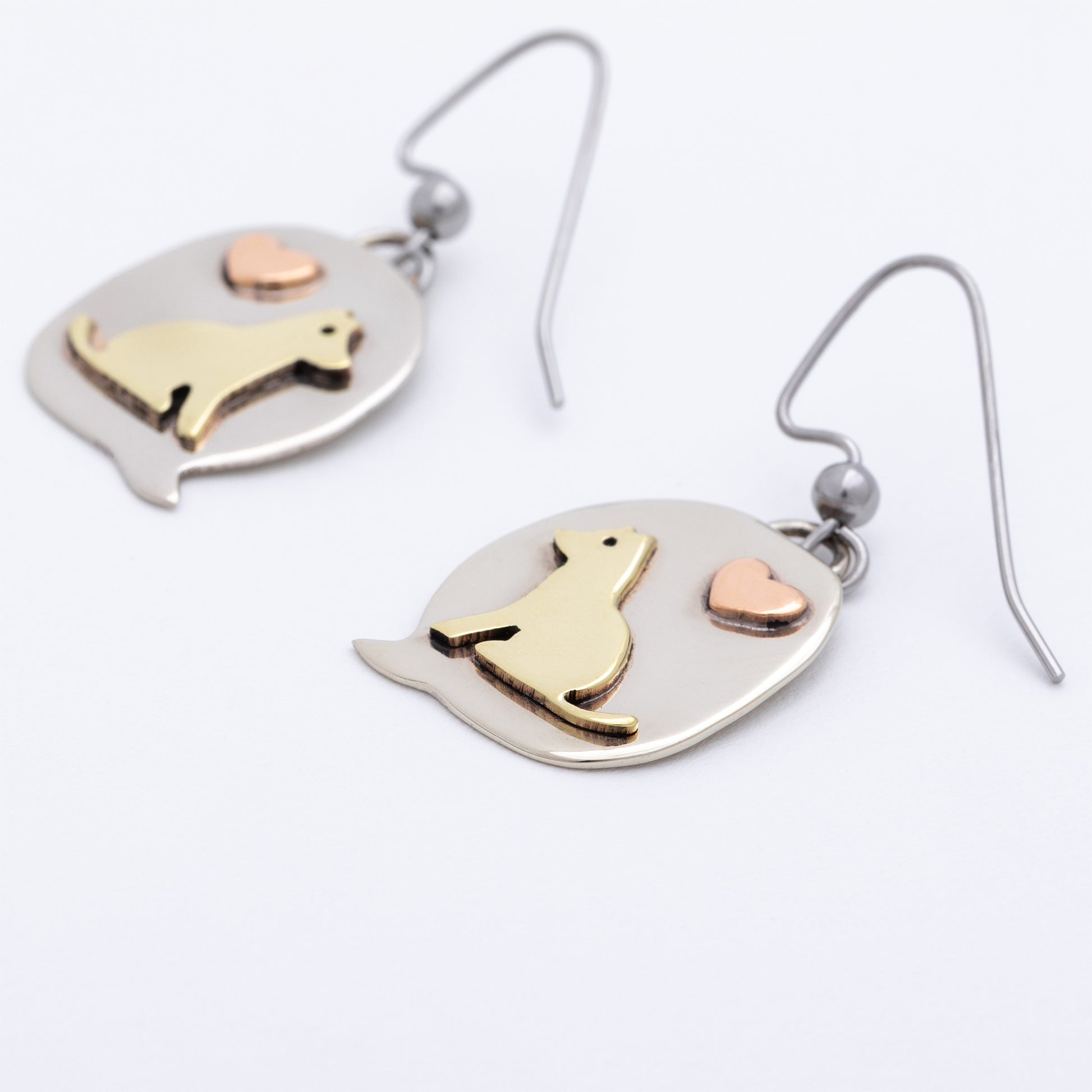 Pair of earrings with dog and heart designs on a white background