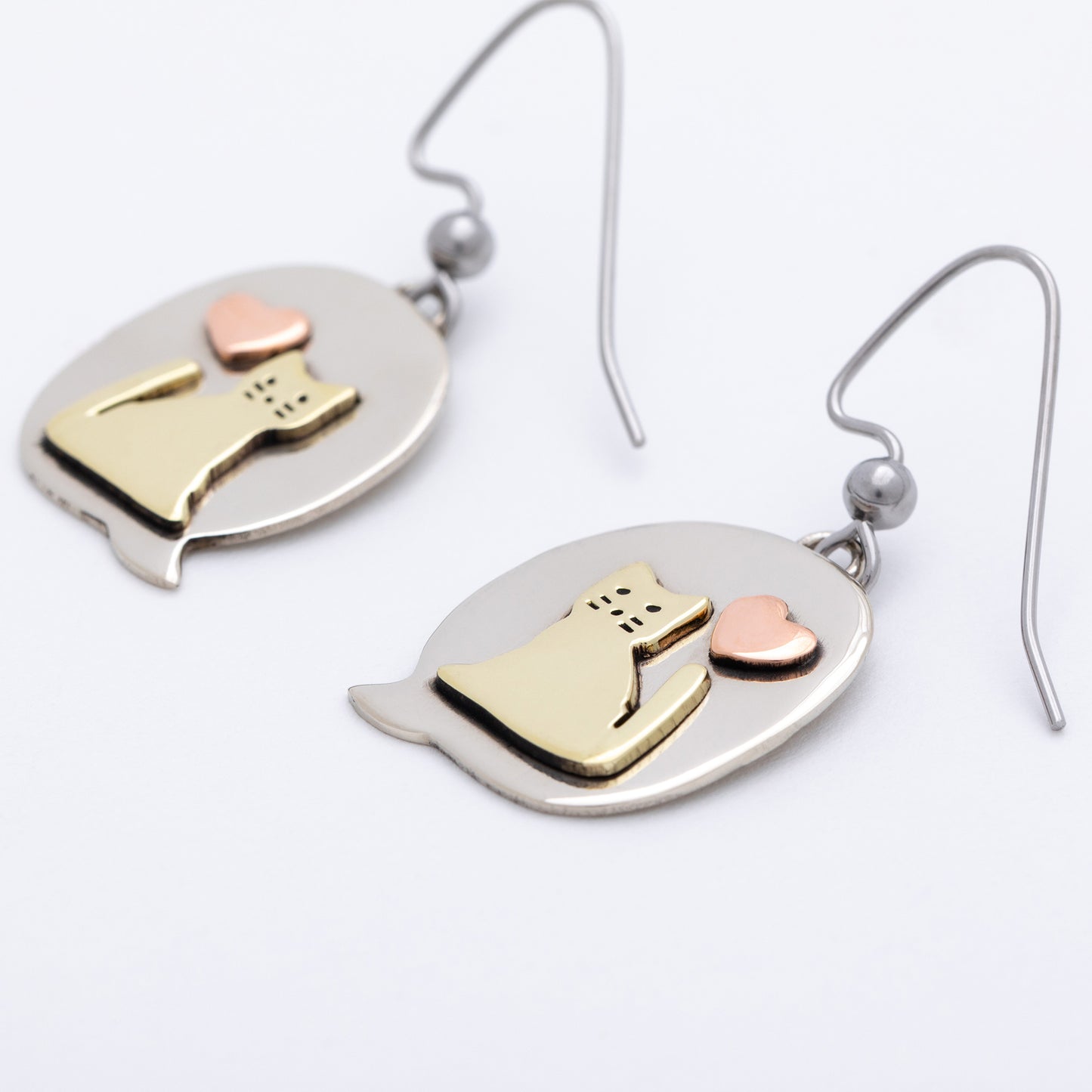 Pair of earrings with cat and heart design on a white background