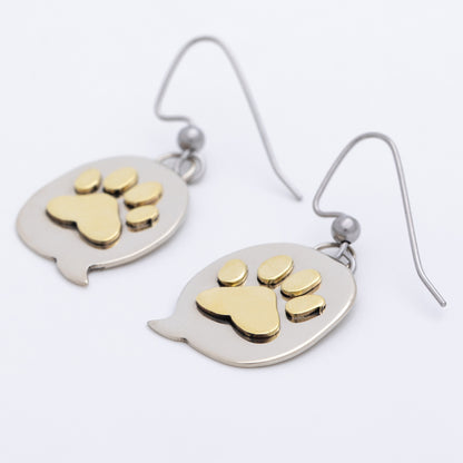 Pair of earrings with brass paw prints on silver oval backgrounds.