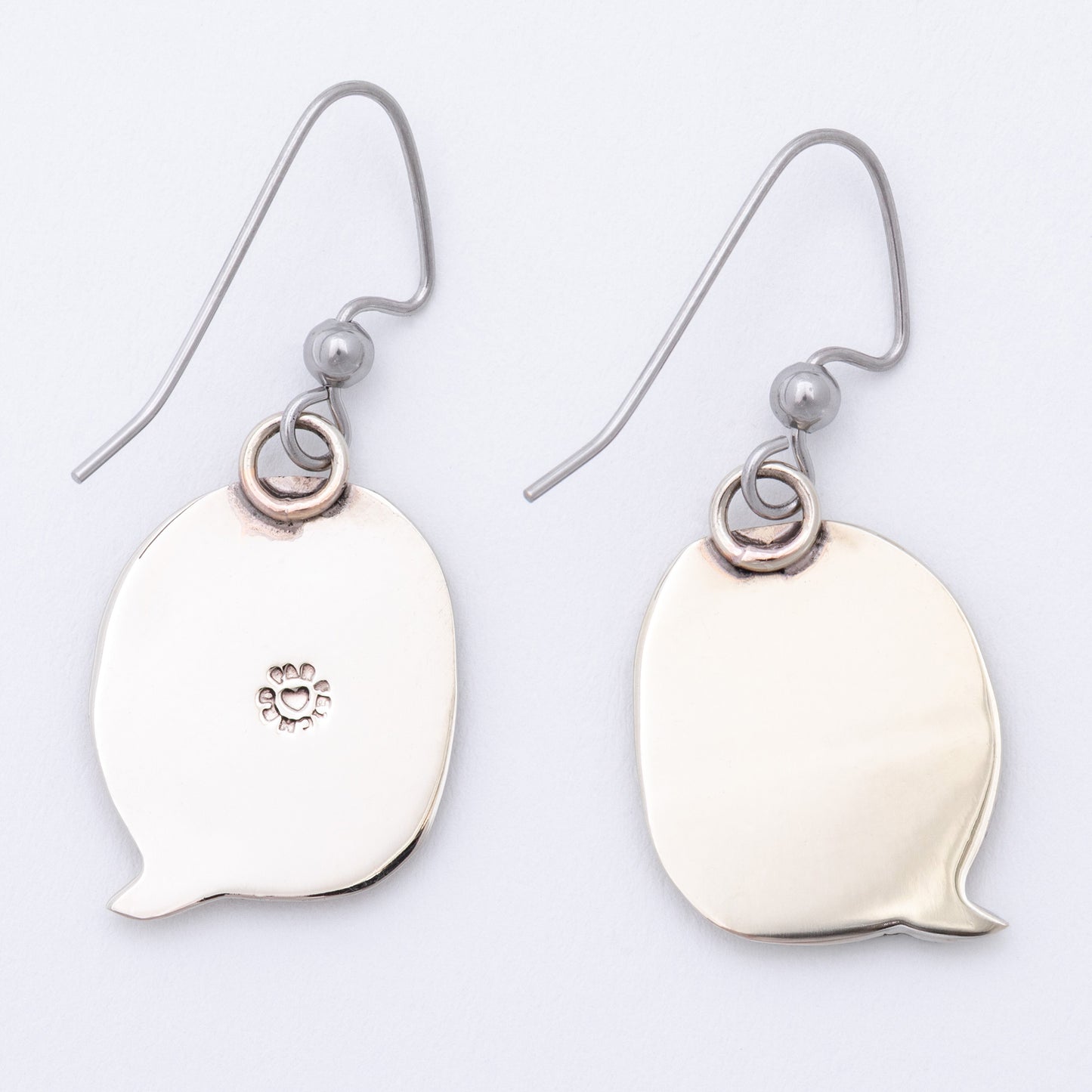 Silver earring backs shaped like speech bubbles on a light gray background.