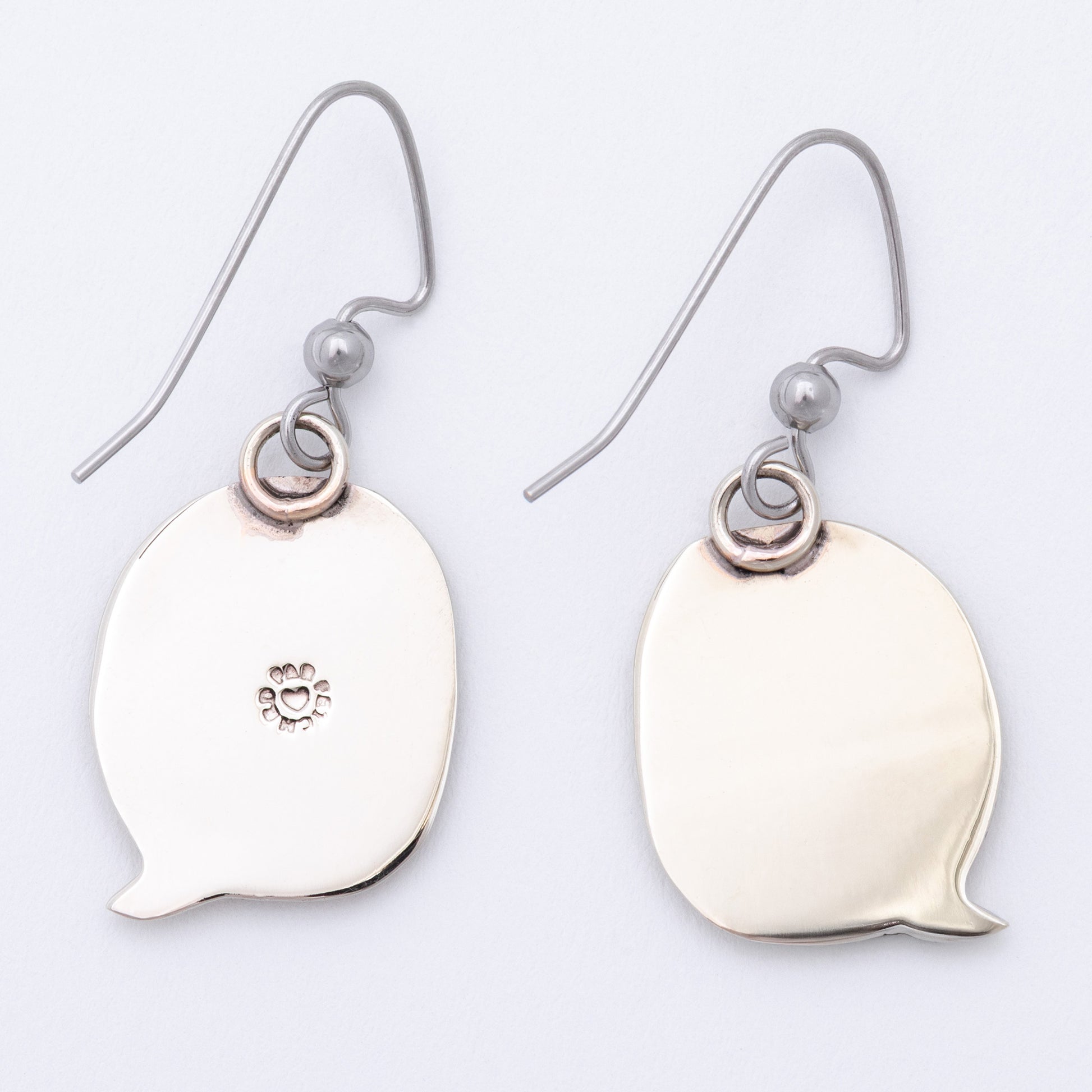 Silver earring backs shaped like speech bubbles on a light gray background.