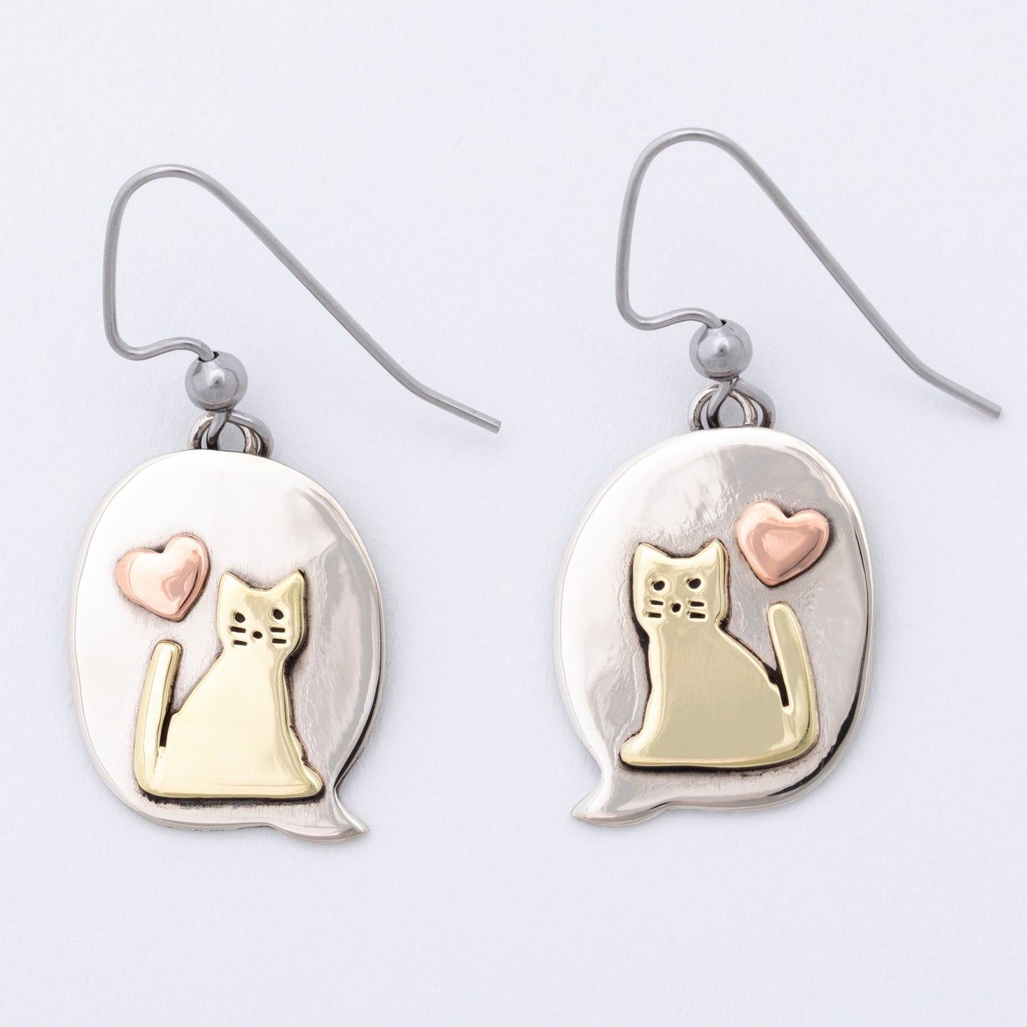 Pair of earrings with cat and heart design on a white background.