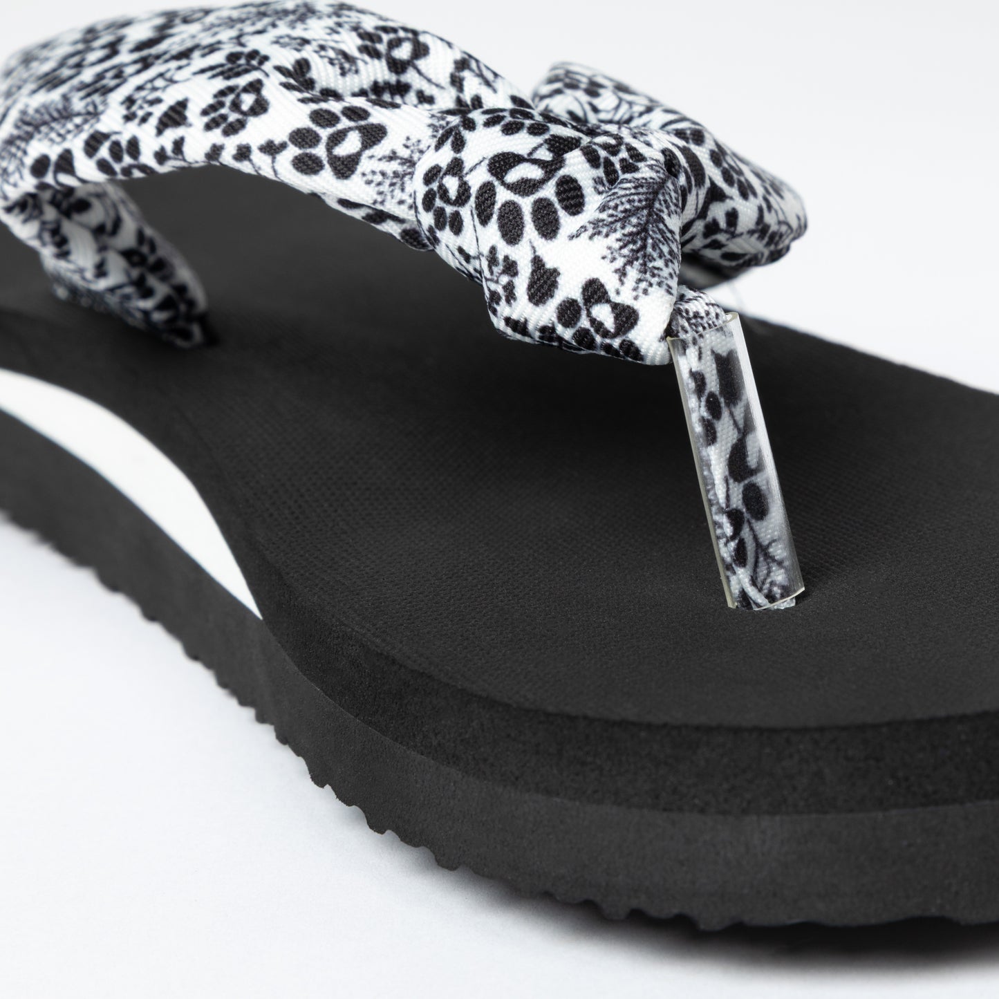 Black sandal with a floral and paw print strap on a white background