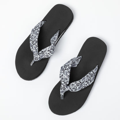 Black flip-flops with floral and paw print design on a white background