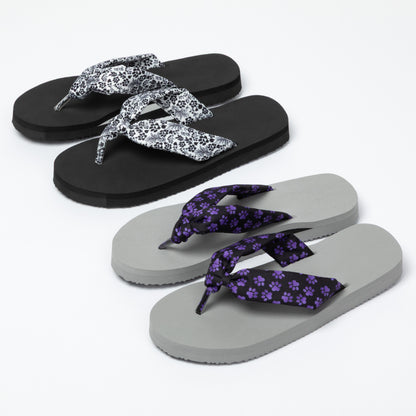 Pair of flip-flops with floral design on straps and gray flip-flops with purple floral design on straps on a white background.