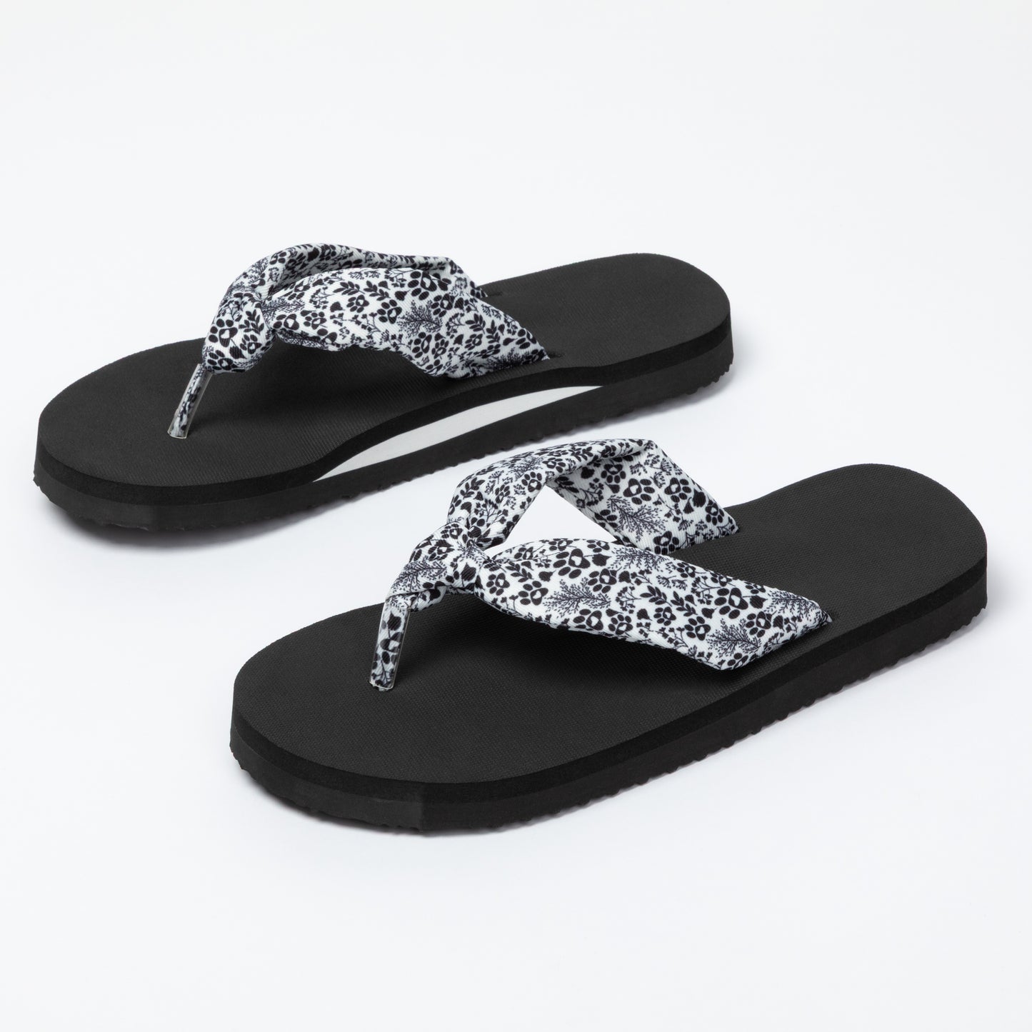 Black flip-flops with white floral patterns on a white background