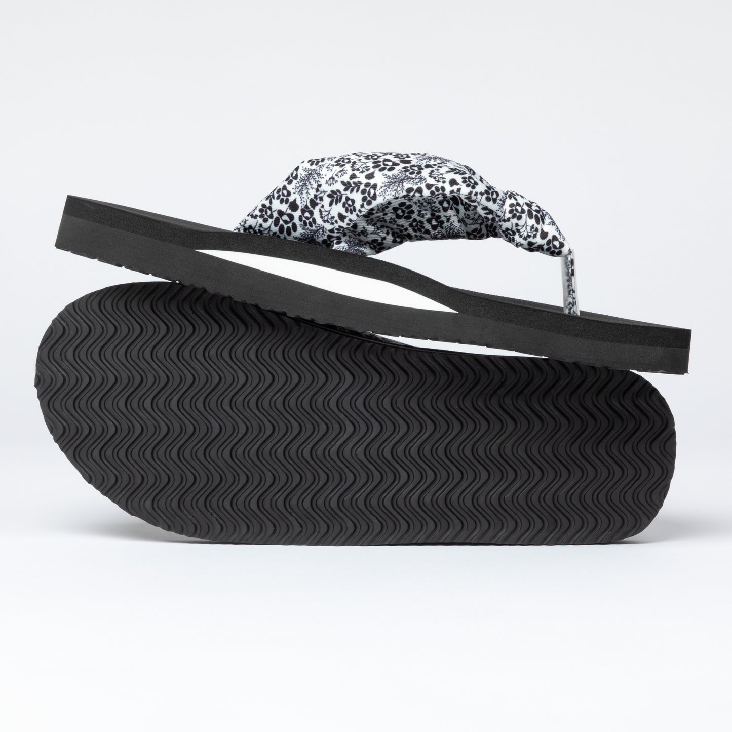 Black sandal with a floral and paw print strap on a white background