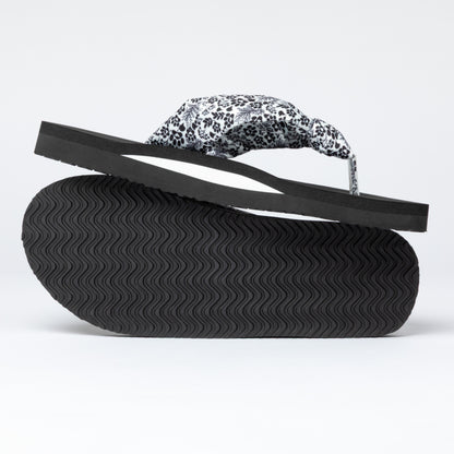 Black sandal with a floral and paw print strap on a white background