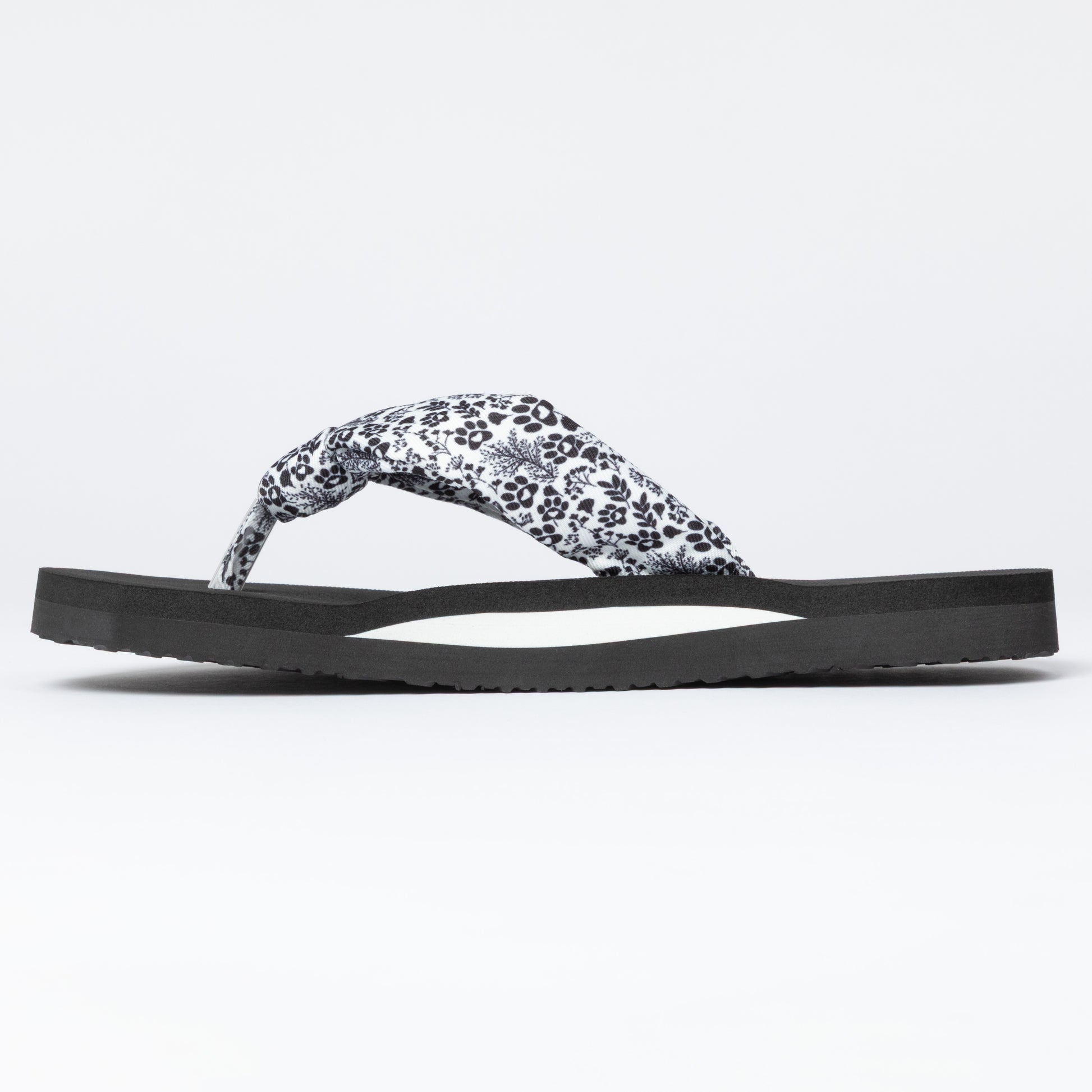 Black sandal with a white floral pattern on a light gray background