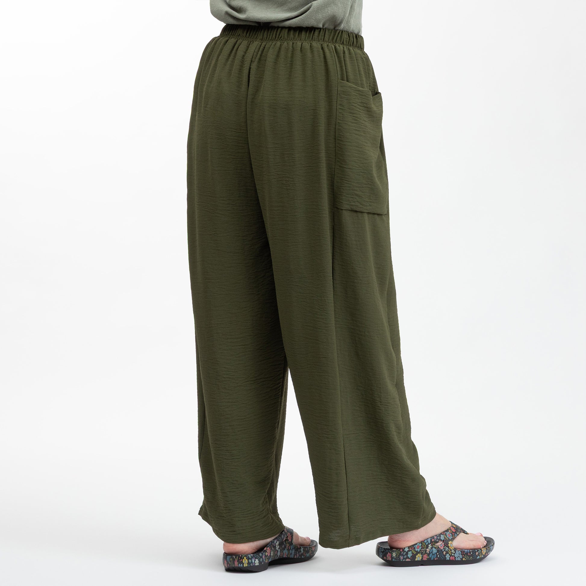 Green wide-leg pants worn by a person on a white background
