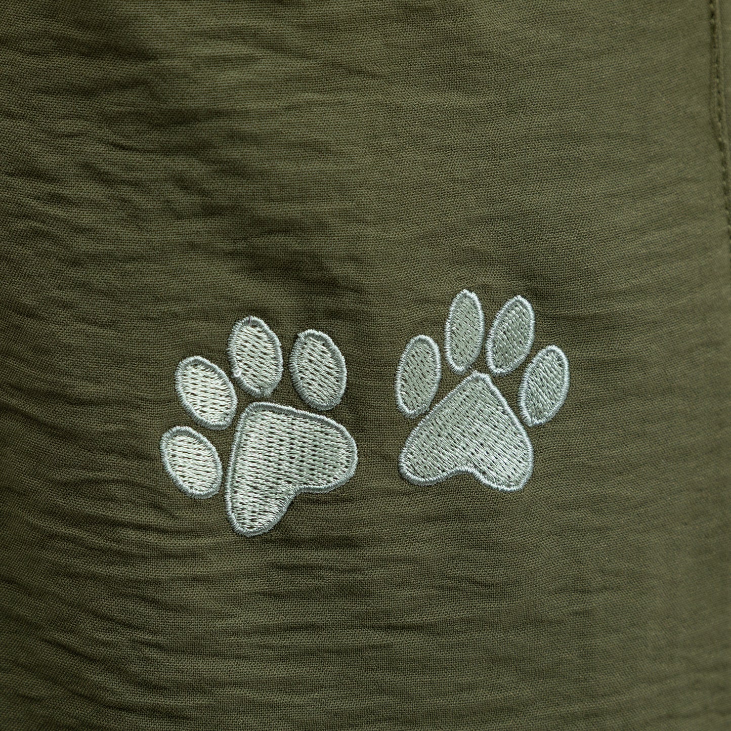 Light green paw prints on a green fabric background